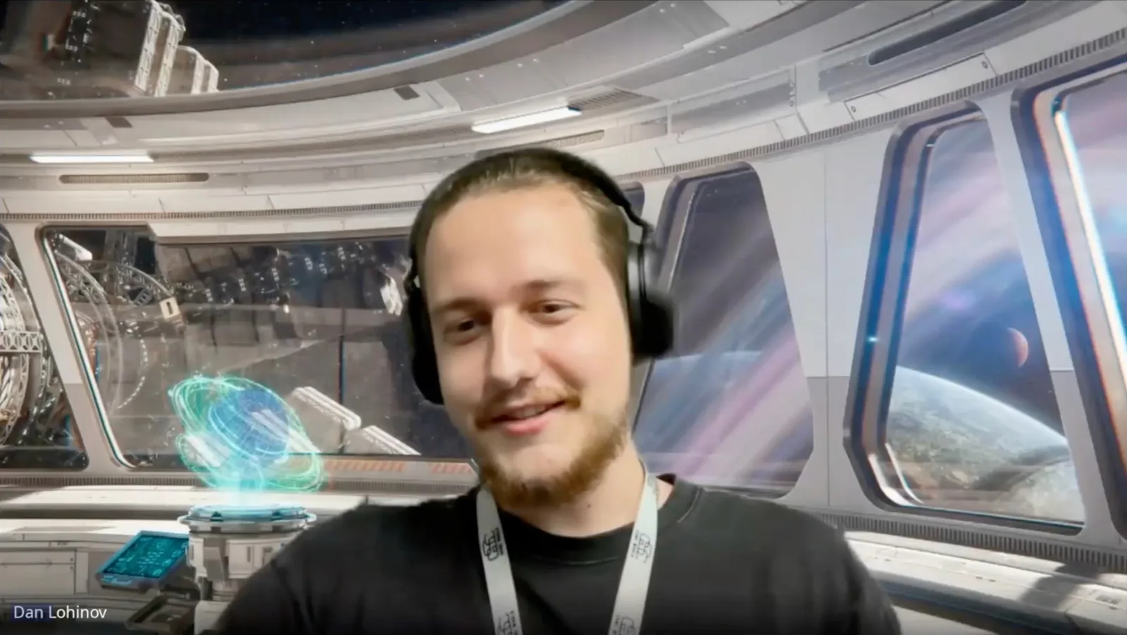A GSC Game World team member on a webcam call in Live Aware, headphones on, in front of a virtual spacecraft-corridor background.