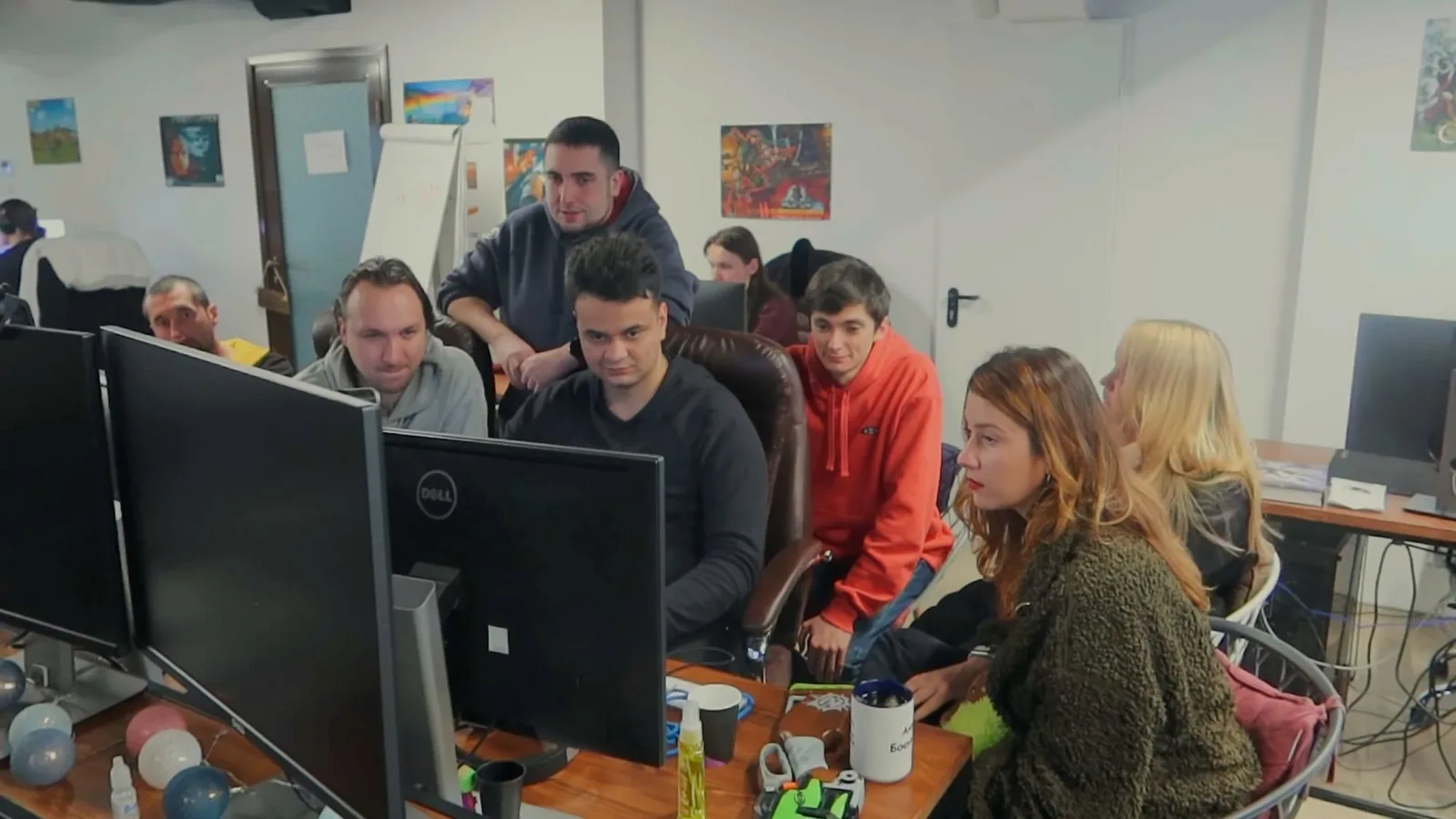 A dozen members of the GSC Game World team crowded around a pair of monitors in their office, watching a build together.